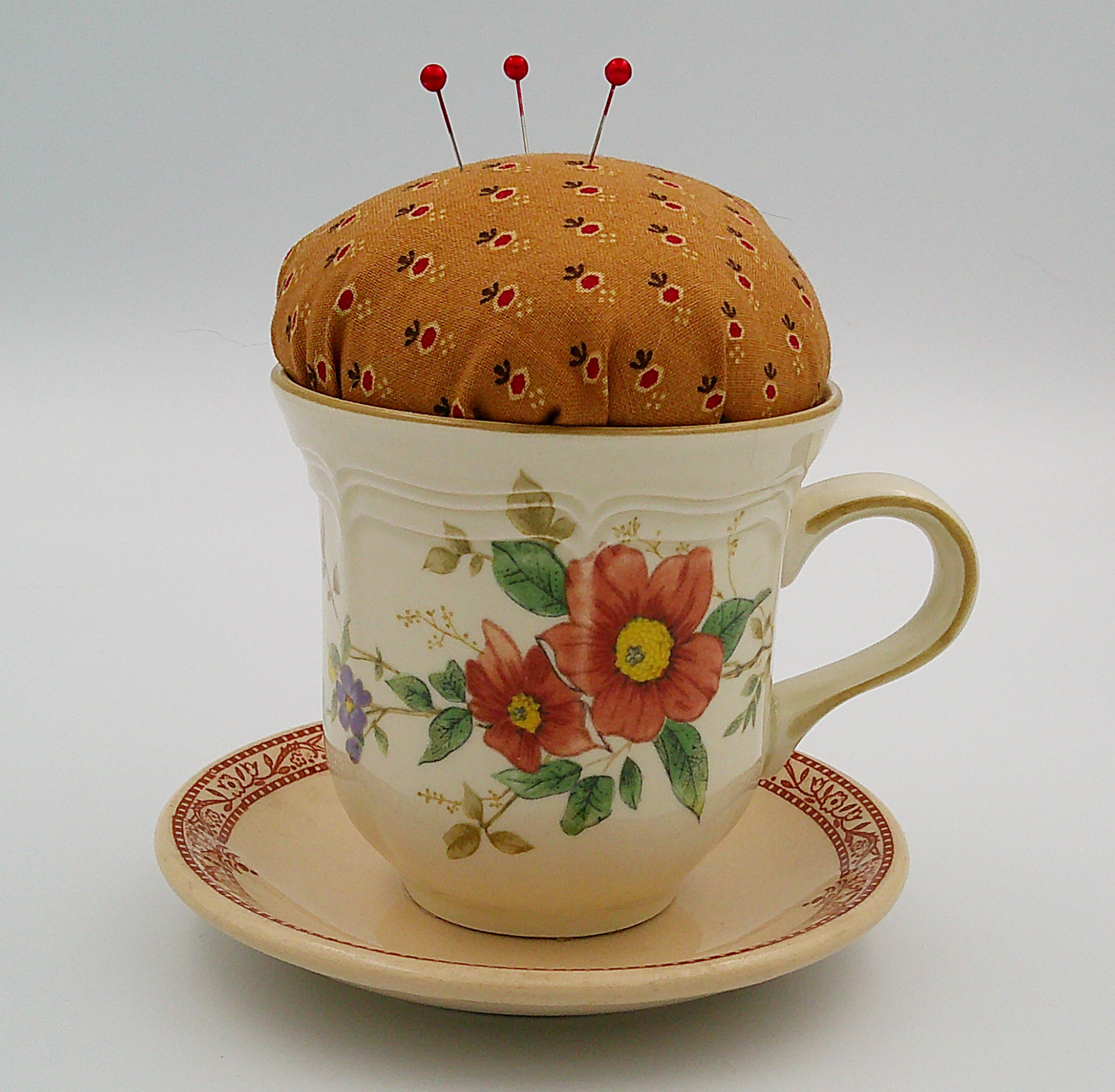 This is the front of the pincushion showing the flowers on the cup as well as the details on the trim of the saucer. This is the front of the pincushion showing the flowers on the cup as well as the details on the trim of the saucer.